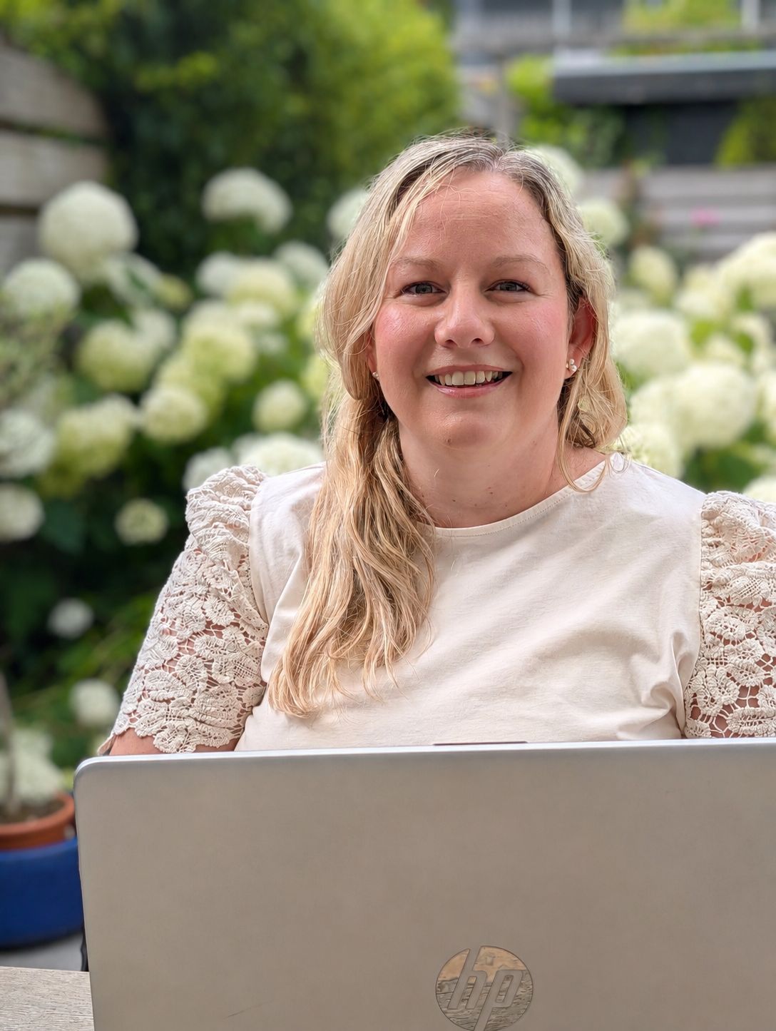 Yana Havelaar smiling behind her laptop in the garden